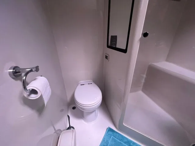 Interior view of a boat's restroom, featuring a modern toilet and shower area, showcasing the amenities available for comfort during fishing trips.