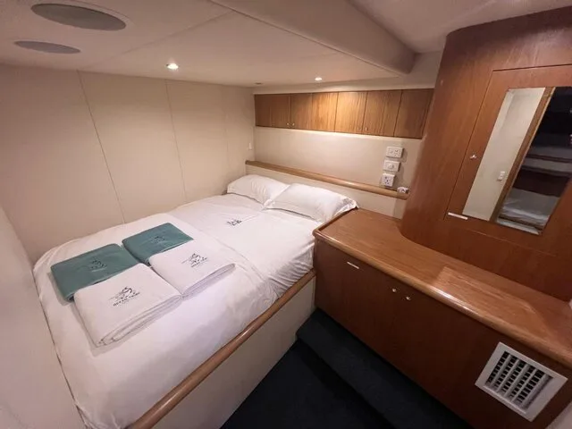 Cozy cabin interior featuring a double bed and storage space, ideal for overnight fishing trips.