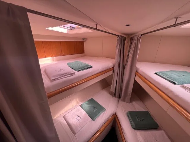 Interior view of a cozy cabin with twin berths and neatly arranged towels, showcasing the comfortable accommodations on a fishing charter boat.