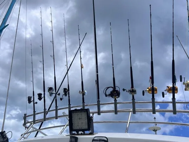A well-equipped fishing boat showcasing multiple rod holders and fishing gear, set against a dramatic cloudy sky.